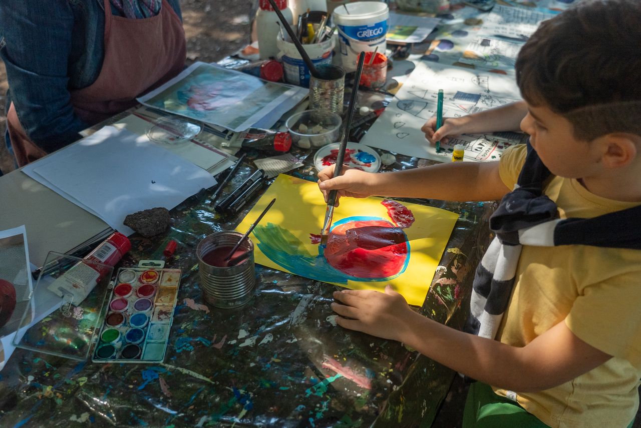 A child painting creatively with watercolors during an outdoor art class.