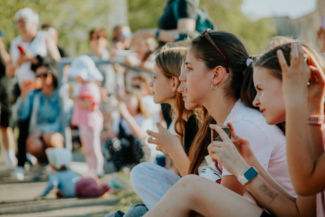 Group of teenagers enjoying an outdoor summer event filled with people and activities.