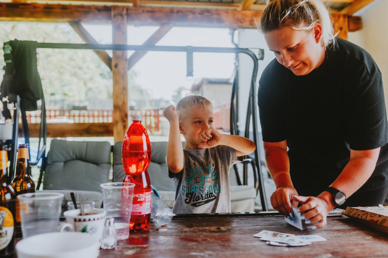 A cheerful moment of a mother and child playing cards outdoors in a backyard.
